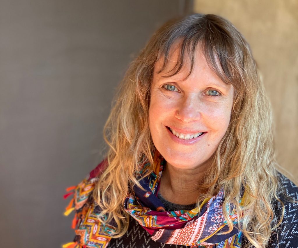 rose cullis wears a colourful scarf and sits on a metal chair smiling